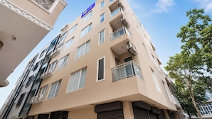 Un edificio de hotel de varios pisos con fachada plana, balcones y cielo despejado.