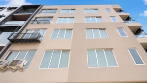 Un edificio de varios pisos con fachada color beige, numerosas ventanas y balcones.