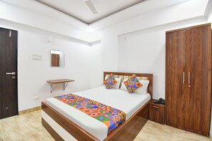 Un dormitorio con cama, mesita de noche, armario y una pequeña estantería.