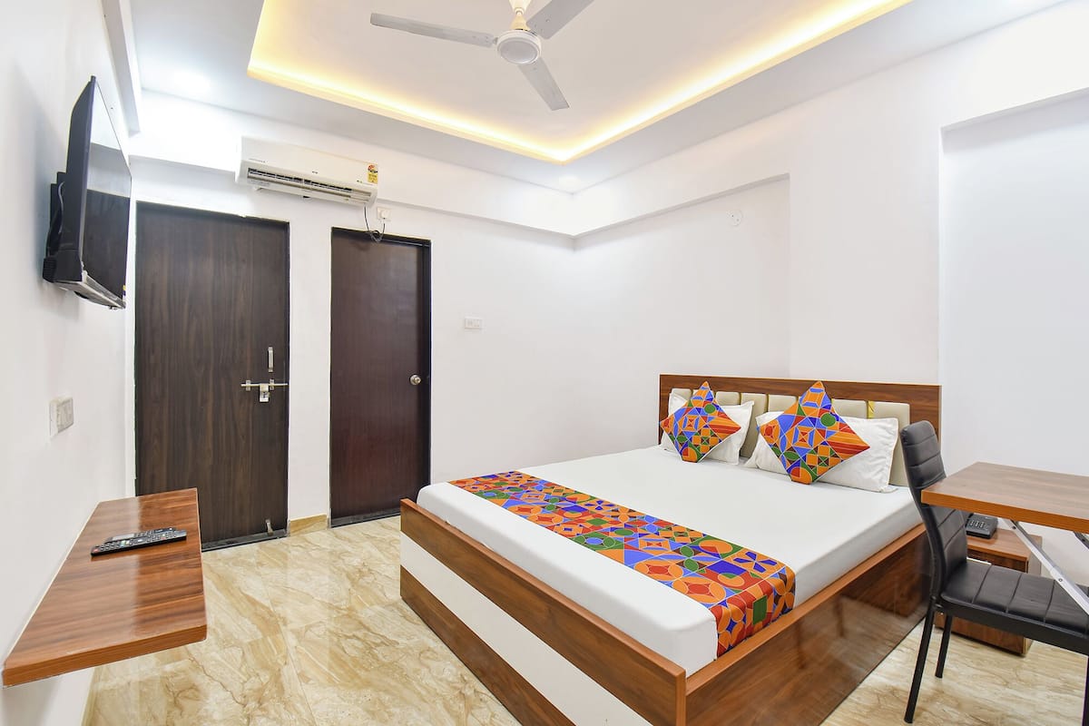 A modern bedroom with a bed, bedside tables, a desk, a chair, a TV, and a ceiling fan.