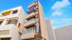 A multi-story building with a prominent 'fab hotels' sign, balconies, and a clear sky.