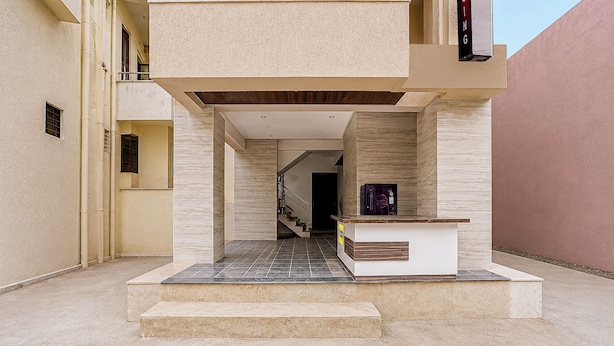 A modern building entrance with a staircase leading to an upper level, a reception desk, and a visible door.