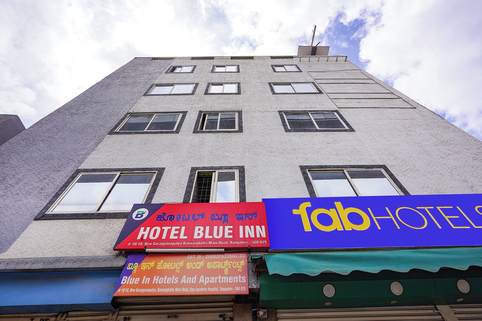 A multi-story building with a sign for 'Hotel Blue Inn' and another sign for 'Blue In Hotels And Apartments.'