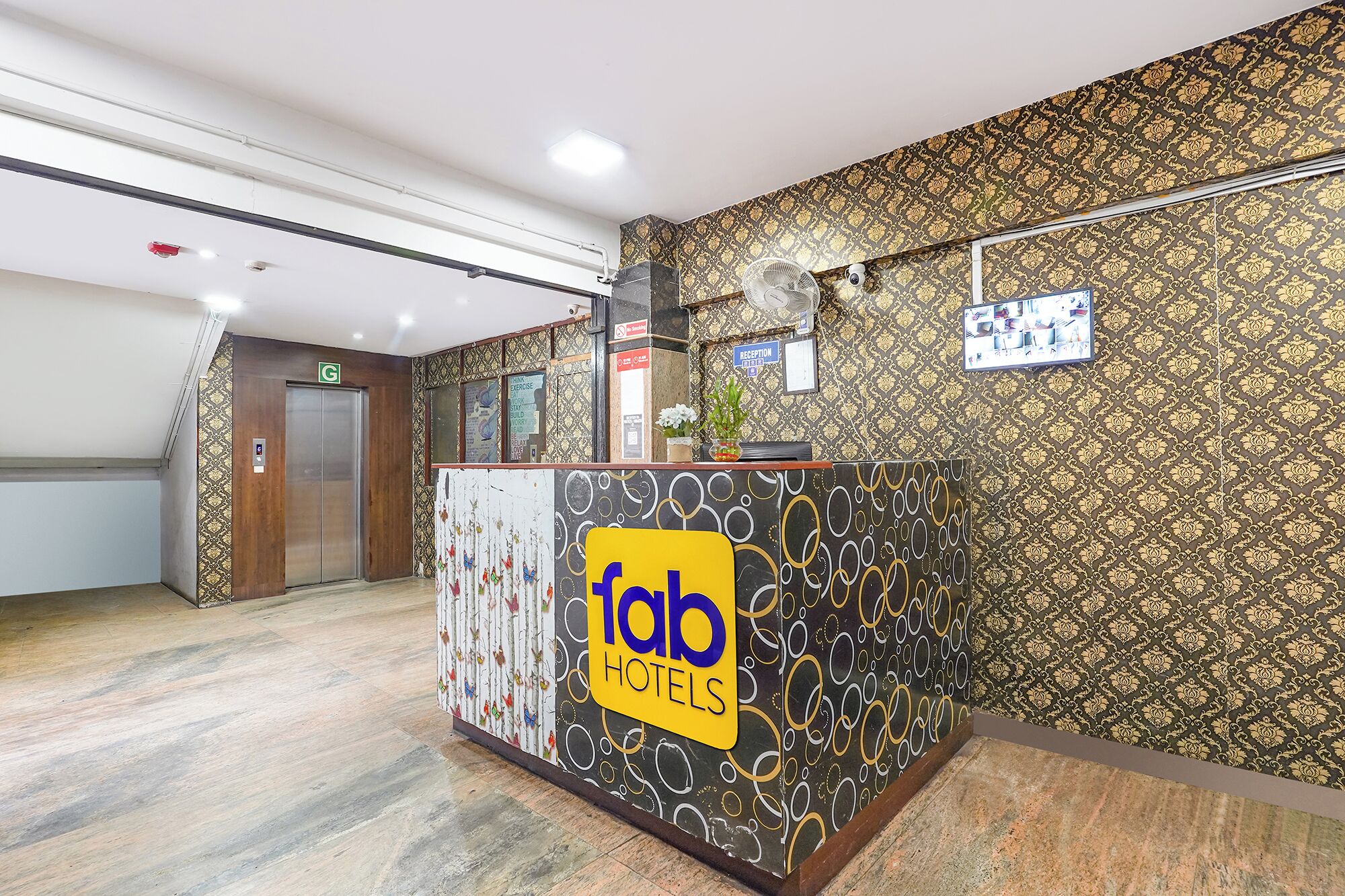 A reception desk with a logo, a reception sign, and an elevator.