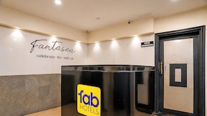 Una recepción con un cartel que dice 'Fab Hotels' y otro cartel que dice 'Hotel Kensington' al fondo.