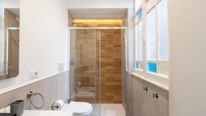 Et moderne badeværelse med brusekabine i glas, toilet og håndvask.