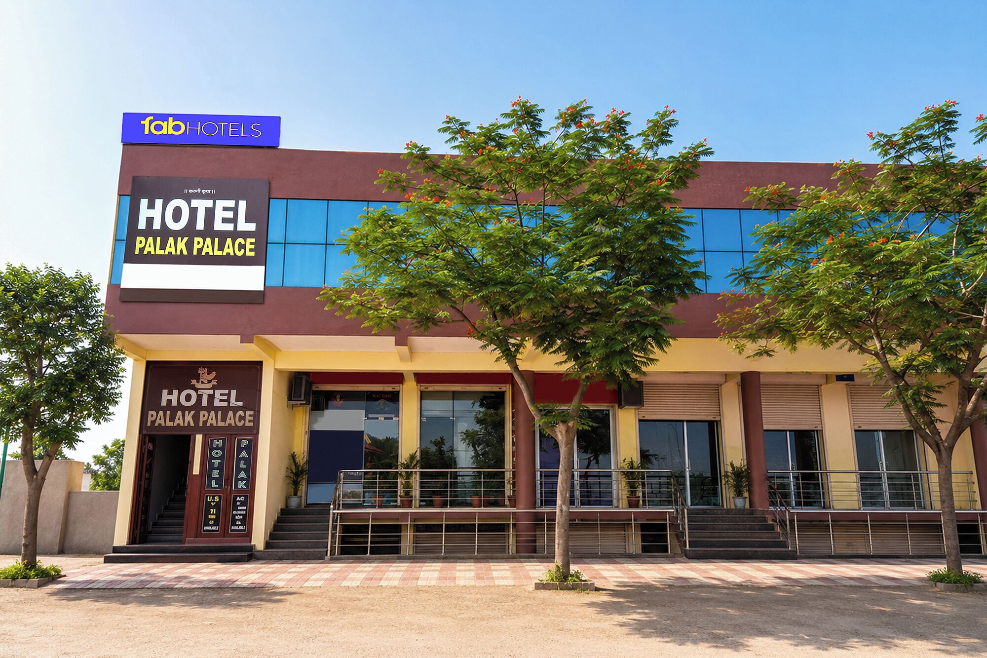Un hôtel avec une enseigne indiquant « HÔTEL PALAK PALACE » et, au-dessus, le nom « fabHOTELS ».