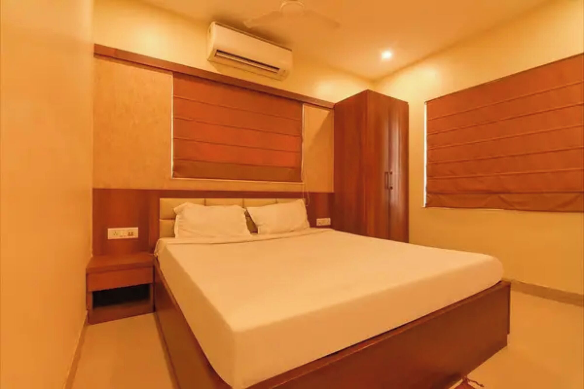 Un dormitorio con cama, aire acondicionado, paneles de madera y mesita de noche.