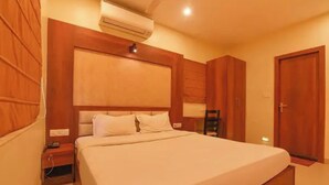 Une chambre à coucher avec un grand lit, une tête de lit en bois, un appareil de climatisation, une table de chevet et une armoire.