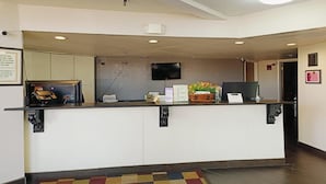 A reception desk with a flat-screen TV, a bulletin board, and a small plant.