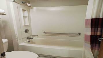 A bathroom with a toilet, a bathtub, and a shower curtain.