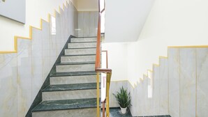 A staircase with marble steps and yellow accents, leading to a landing with a potted plant.