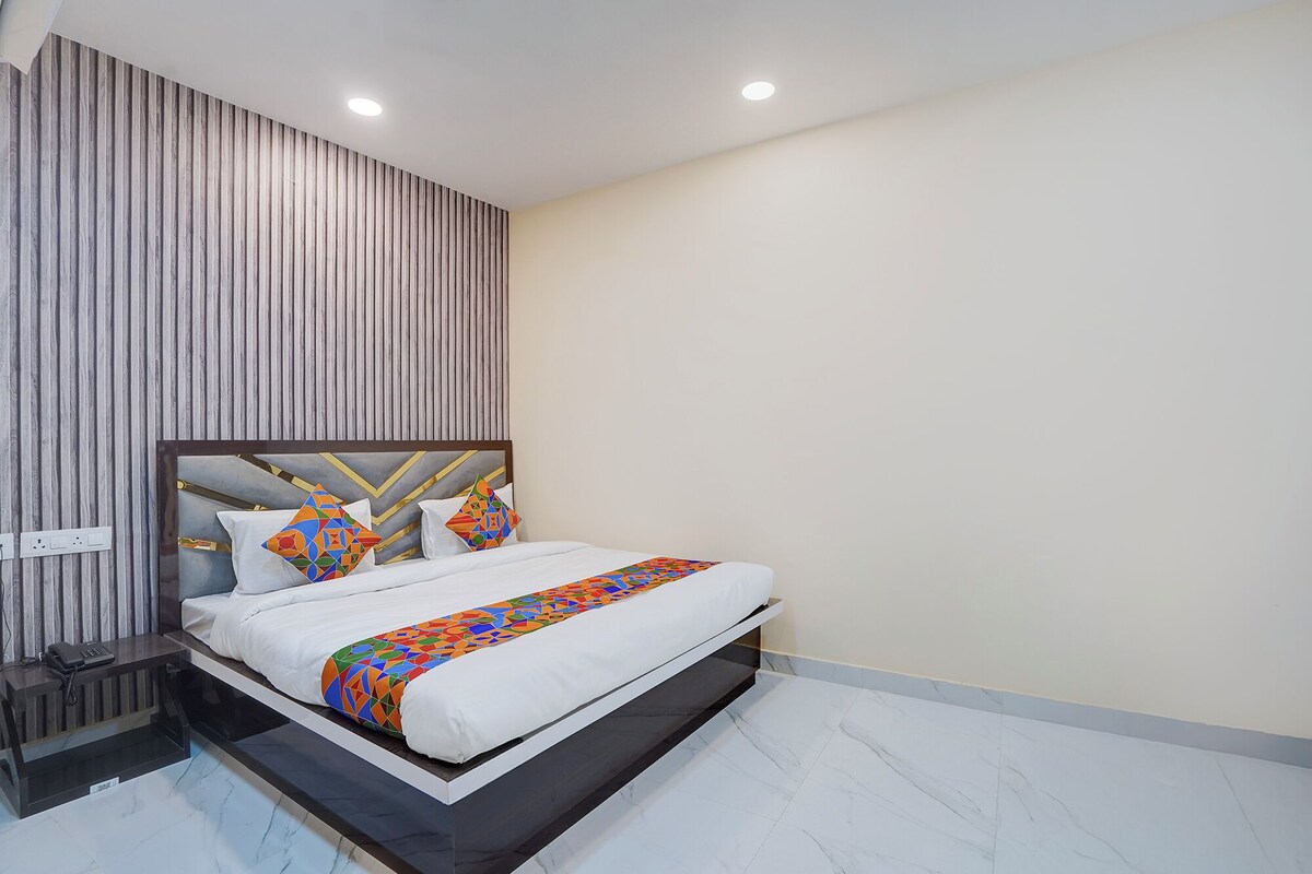 Un dormitorio moderno con cama, mesita de noche y pared con líneas verticales.