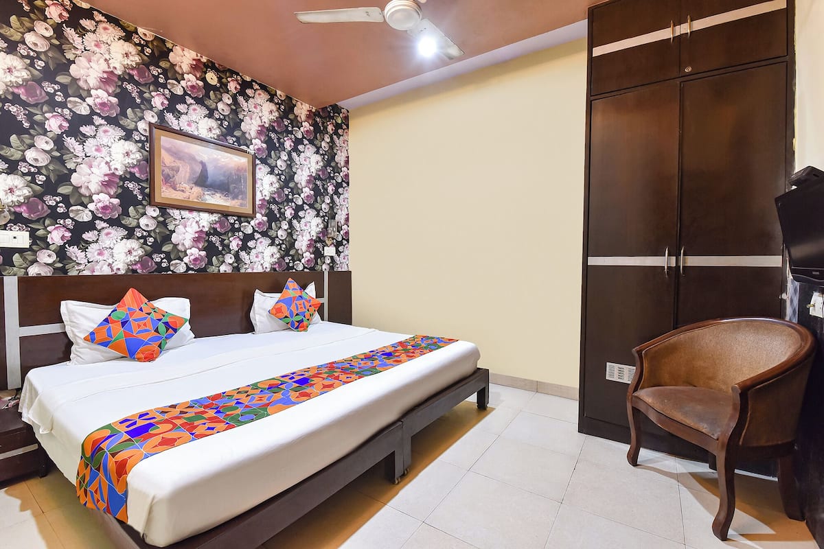 Quarto de hotel com cama, cadeira, guarda-roupa e ventilador de teto.