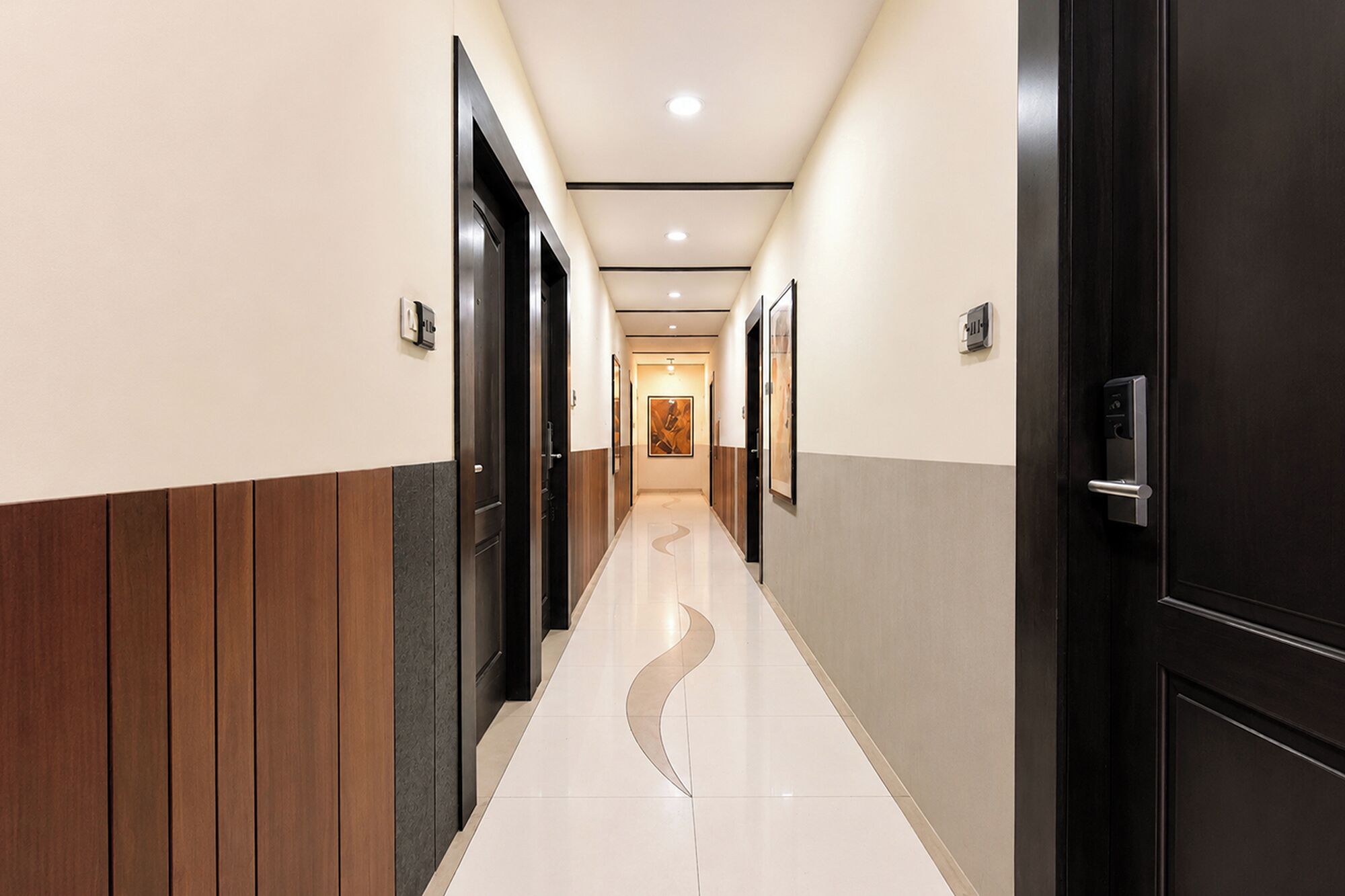 A hotel hallway with wooden paneling, black doors, and a tiled floor.