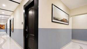 A hallway with a black door, a framed picture on the wall, and a tiled floor. - Fabhotel Ak Acacia Jazz Club (Jaipur)