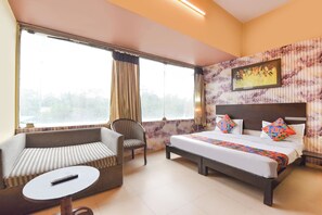 Una habitación de hotel con una cama, un sofá, una silla y una mesita.