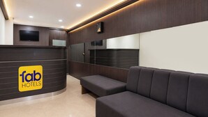 A hotel reception area with a curved reception desk, a sofa, and a large mirror. - Fabhotel Ak Acacia Jazz Club (Jaipur)