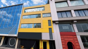 A multi-story building with a yellow facade, a blue glass section, and a red entrance. - Fabhotel Ak Acacia Jazz Club (Jaipur)