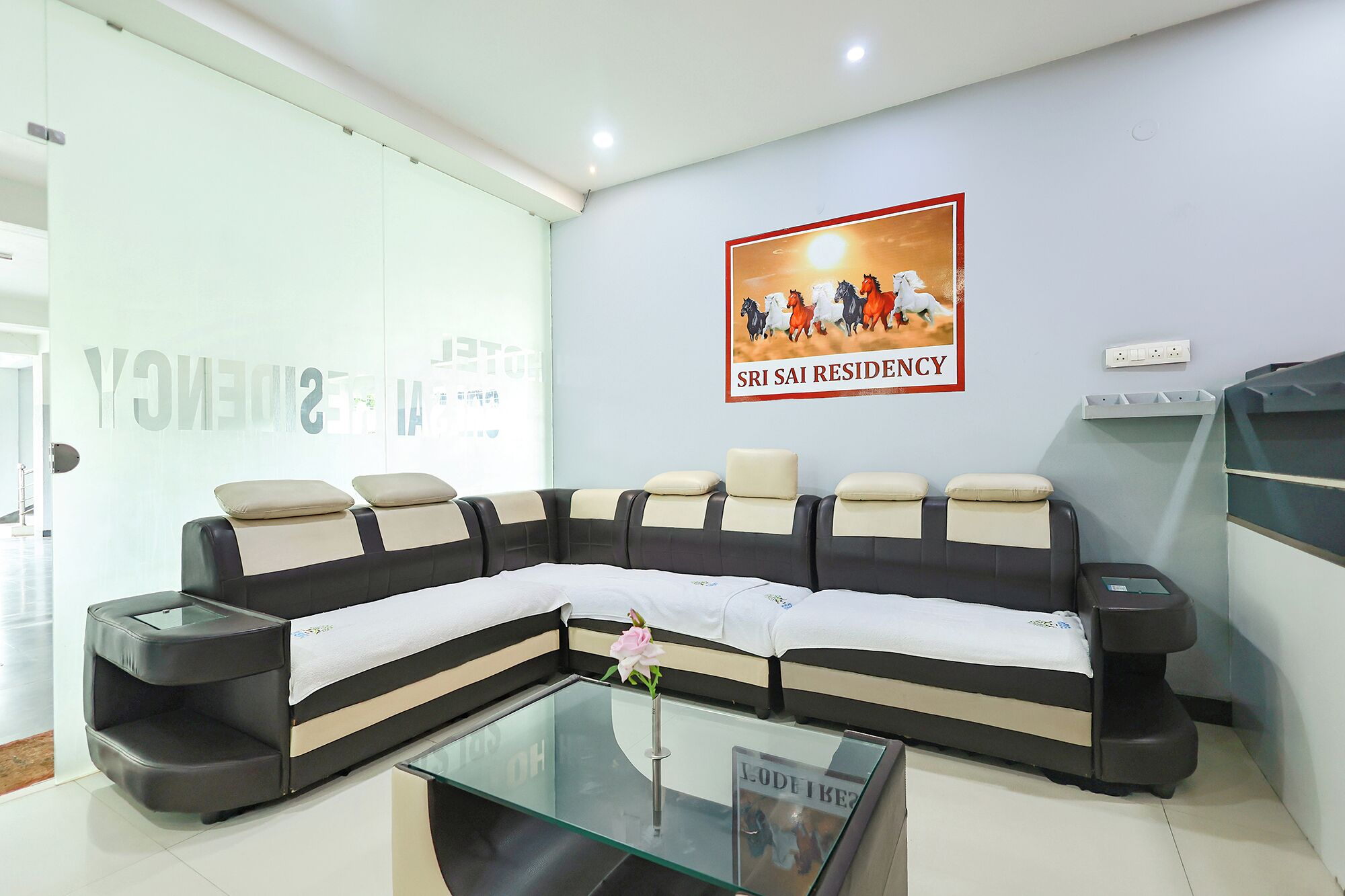 A modern waiting area with a large sofa, a glass coffee table, and a poster on the wall.