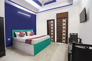 A bedroom with a bed, a chair, a television, and a door. - FabHotel As Residency (Noida)