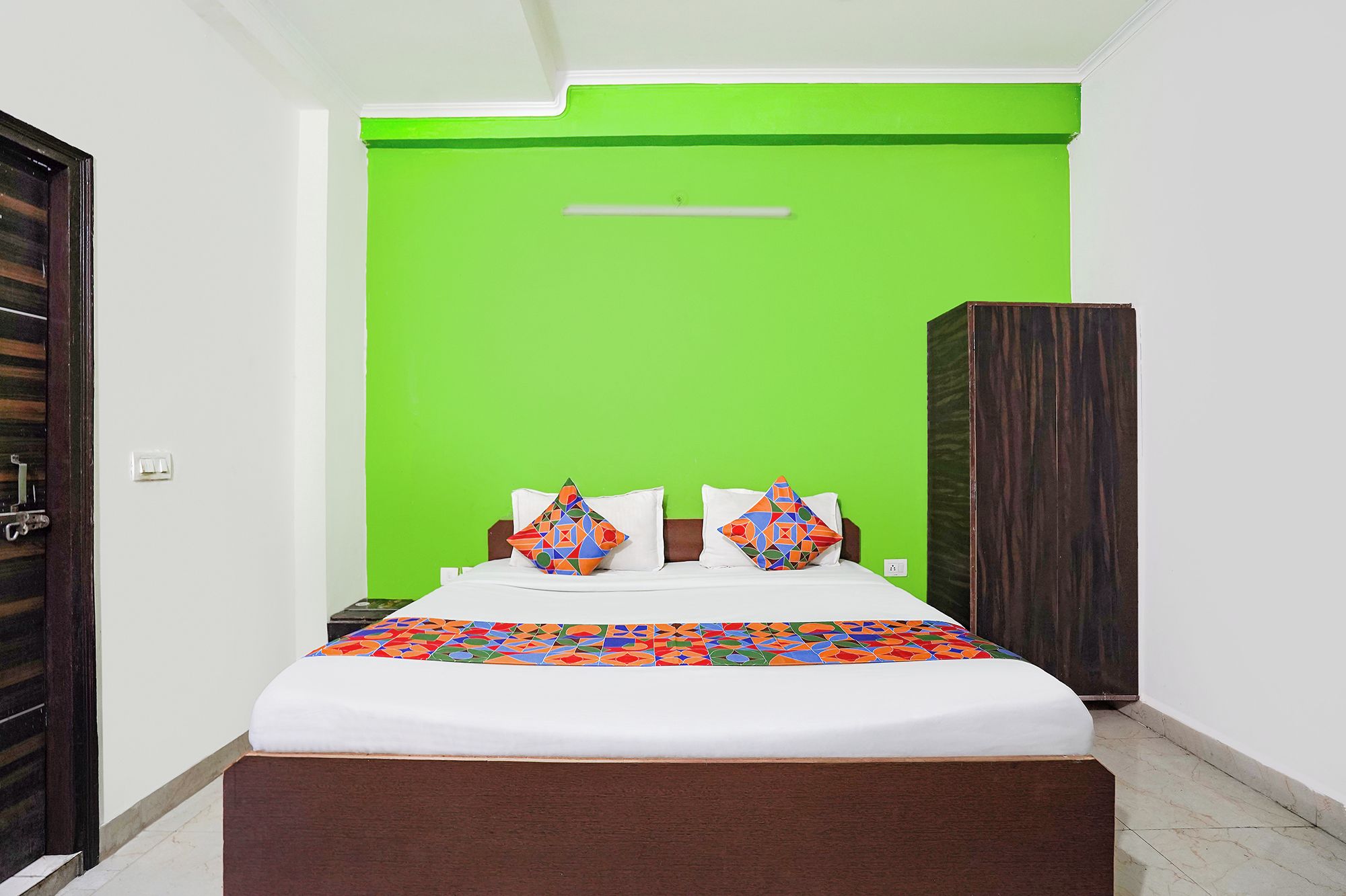 A bedroom with a bed, pillows, and a green accent wall.
