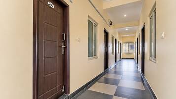 A corridor with a checkered floor, doors, and windows.