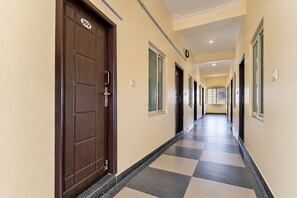 A corridor with a checkered floor, doors, and windows.
