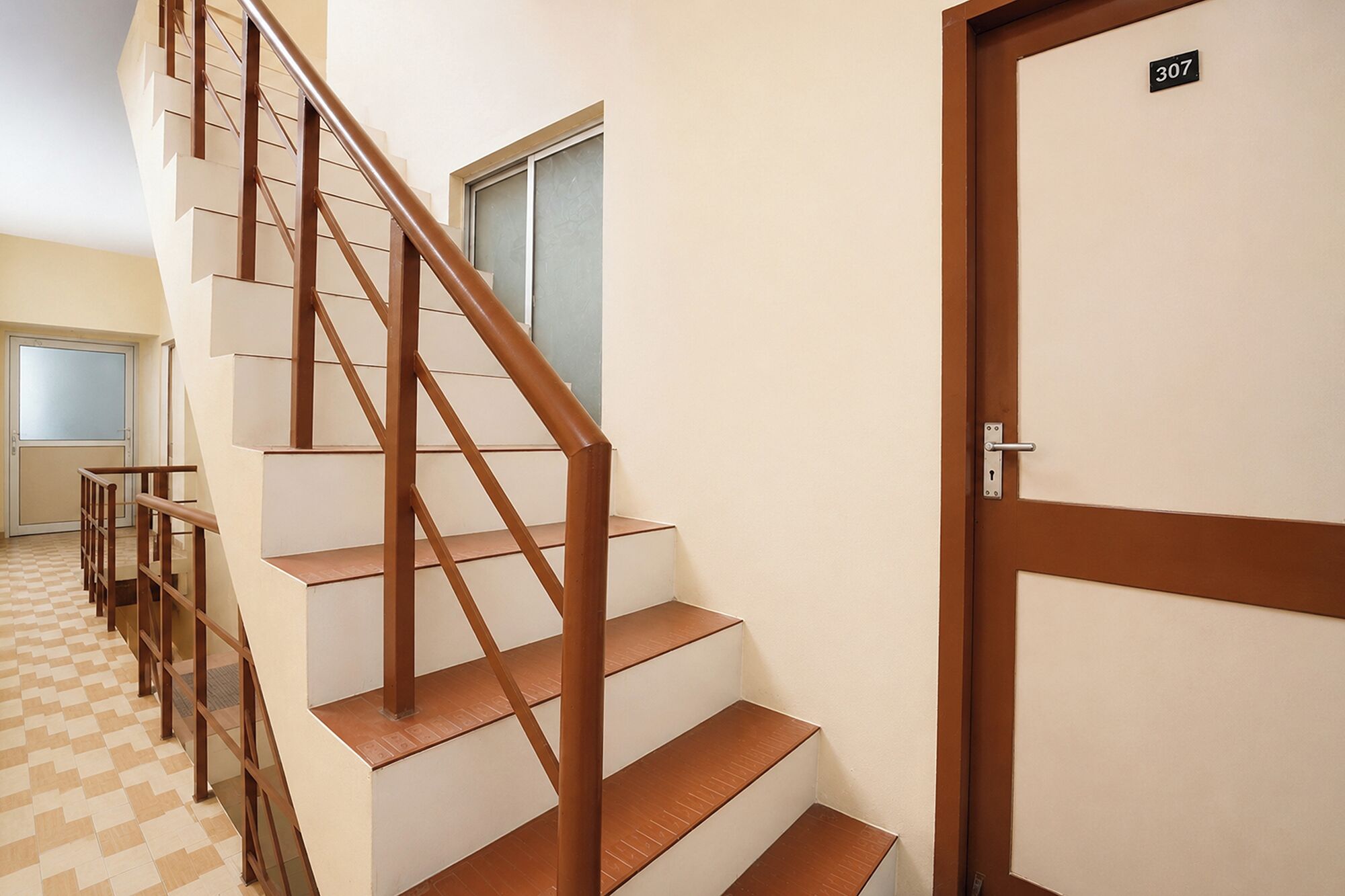 A staircase with wooden handrails and a door marked '307' on the right.
