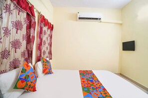 A hotel room with a bed, curtains, pillows, an air conditioning unit, and a flat-screen TV. - Fabhotel Mara Residency (Tirupporur)