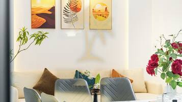 Uma sala de jantar moderna com uma mesa branca, cadeiras cinzentas e um sofá ao fundo.