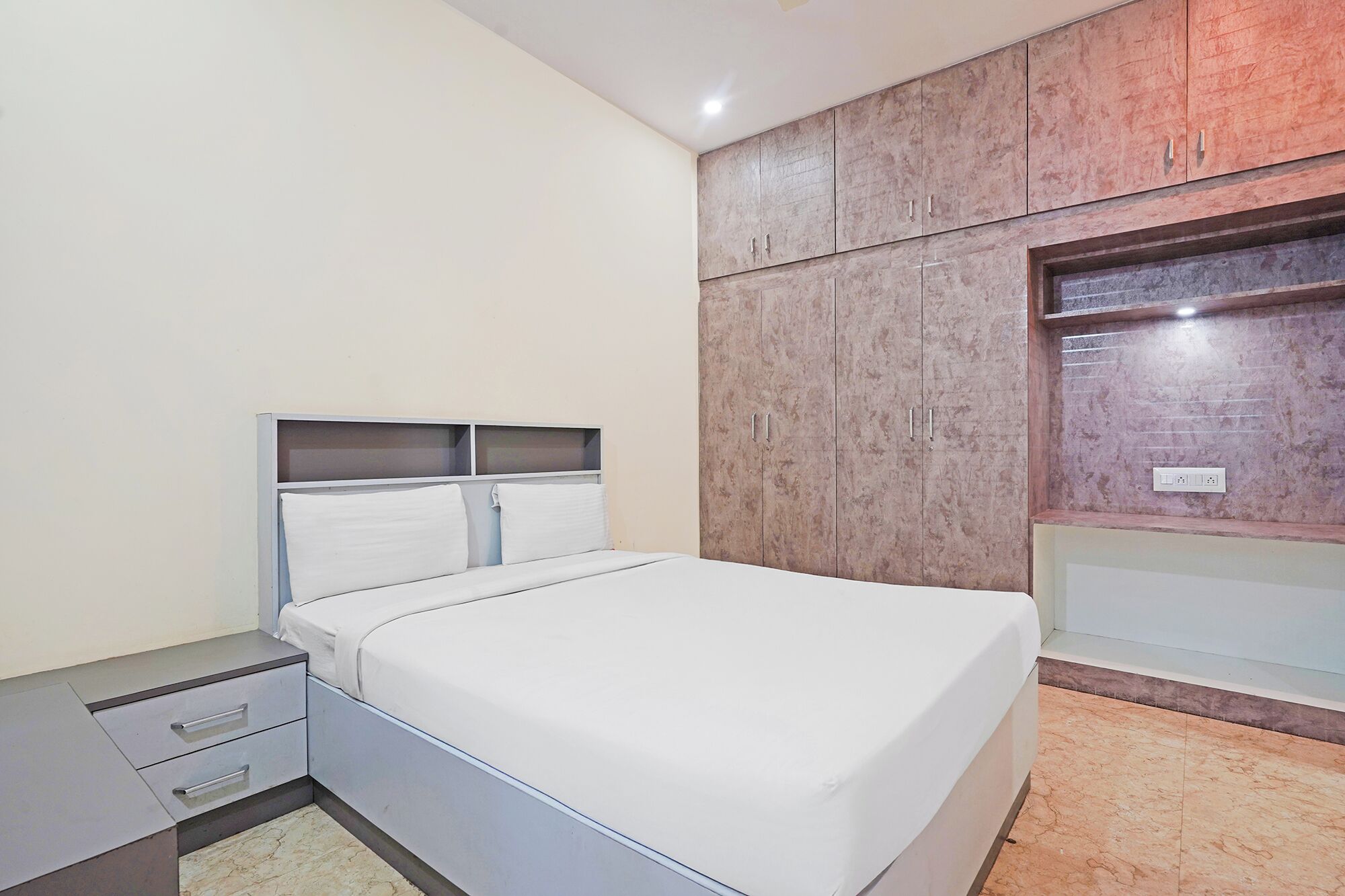 A bedroom with a bed, a wardrobe, and a built-in bench with a mirror.