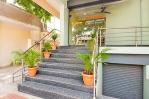 Una escalera con plantas en macetas, una puerta enrollable cerrada y un letrero que indica un establecimiento de alojamiento.