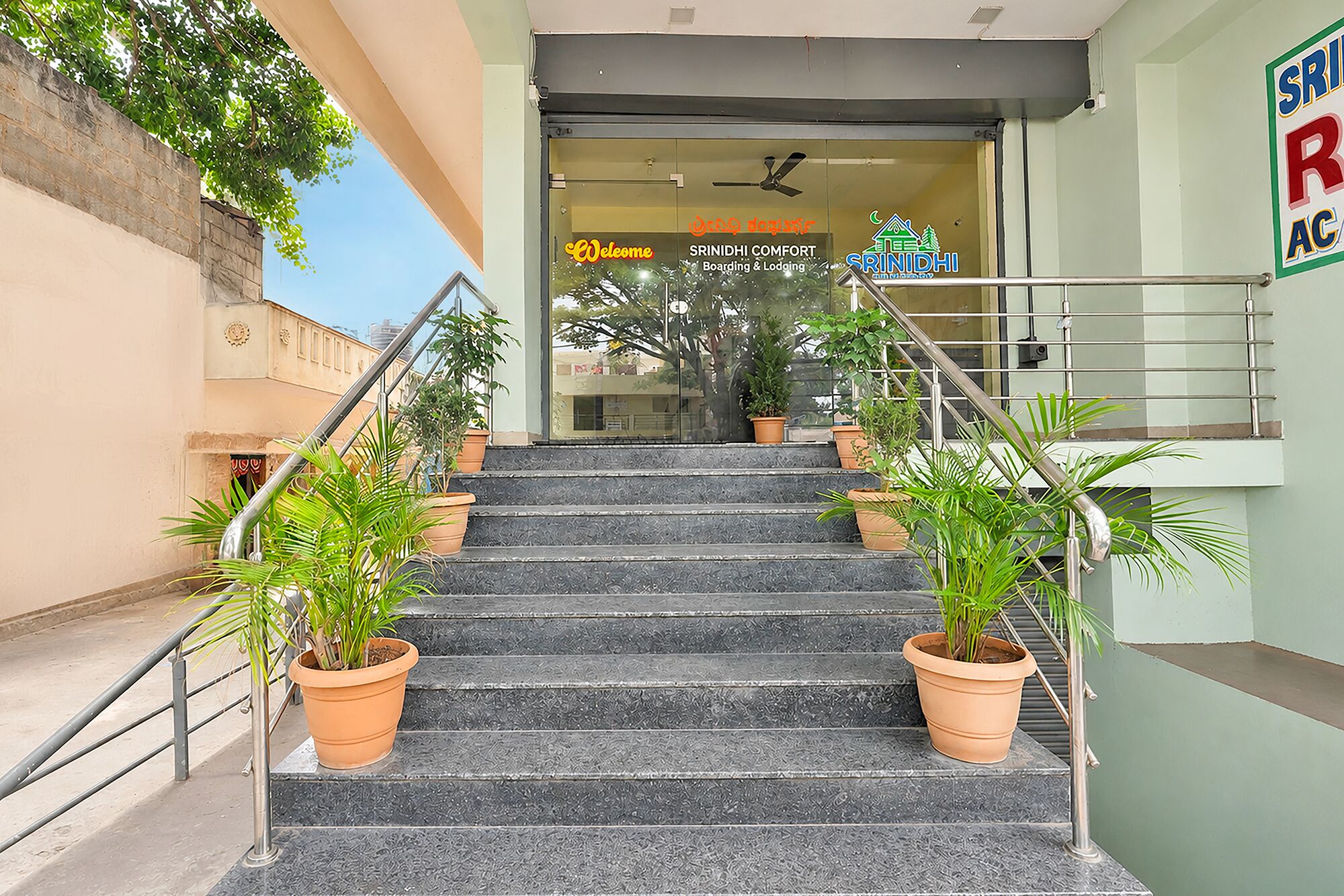 A staircase leading to a hotel entrance with potted plants on either side.