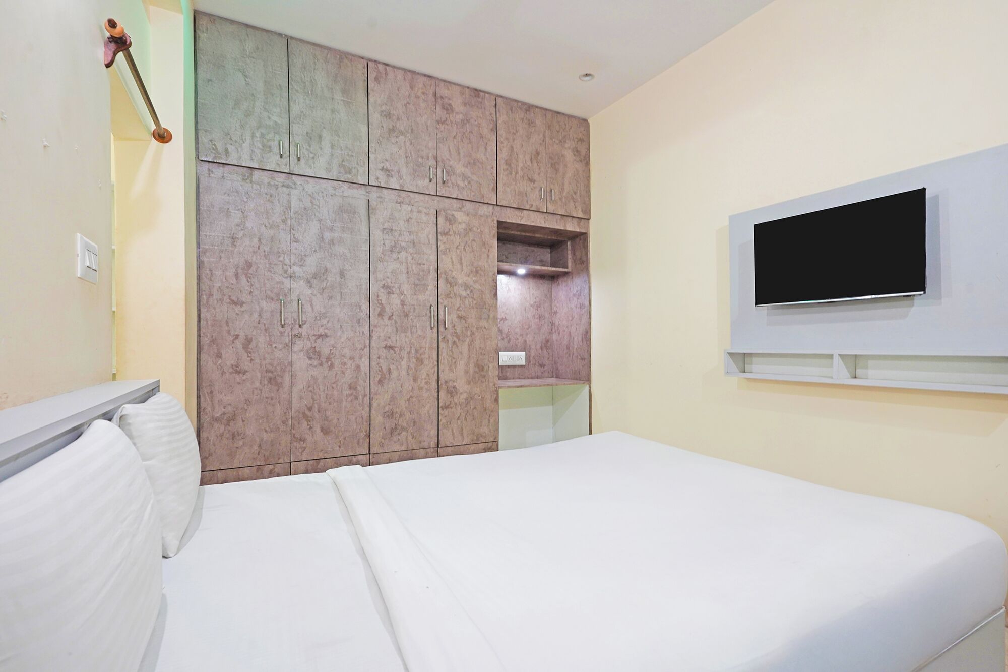 Quarto com cama, guarda-roupa e televisão.