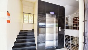 A staircase leading to an elevator, a fire extinguisher on the wall, and a security gate. - Fabhotel Himalay Guest House Saanvi Residency (Pune)