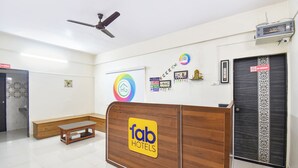 A hotel reception area with a wooden reception desk, a ceiling fan, and a first aid box sign on the wall. - Fabhotel Himalay Guest House Saanvi Residency (Pune)
