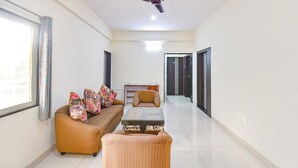 A modern living room with a sofa, armchairs, a glass coffee table, and a ceiling fan. - Fabhotel Himalay Guest House Saanvi Residency (Pune)