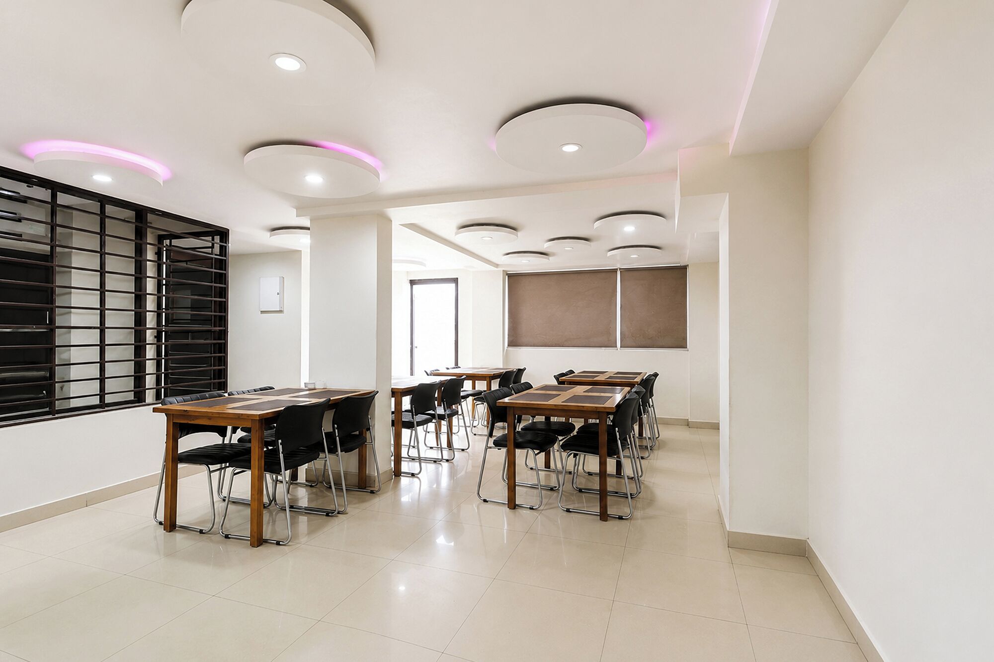 Une salle de conférence équipée de tables rondes, de chaises et de luminaires encastrés au plafond.