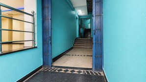 Un couloir aux murs de couleur turquoise, doté d’un sol en marbre noir et d’un escalier menant à un autre niveau.