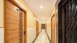 Um corredor de hotel com portas de madeira, parede estampada e chão de mármore.