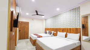 Quarto de hotel com duas camas, um ventilador de teto, parede estampada e um espelho.