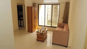 A living room with a sofa, a wooden cabinet, and a small table. - Fabhotel Aqua Pearl Inn (Panvel)