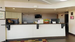 A reception desk with a flat-screen TV, a bulletin board, and a small plant.