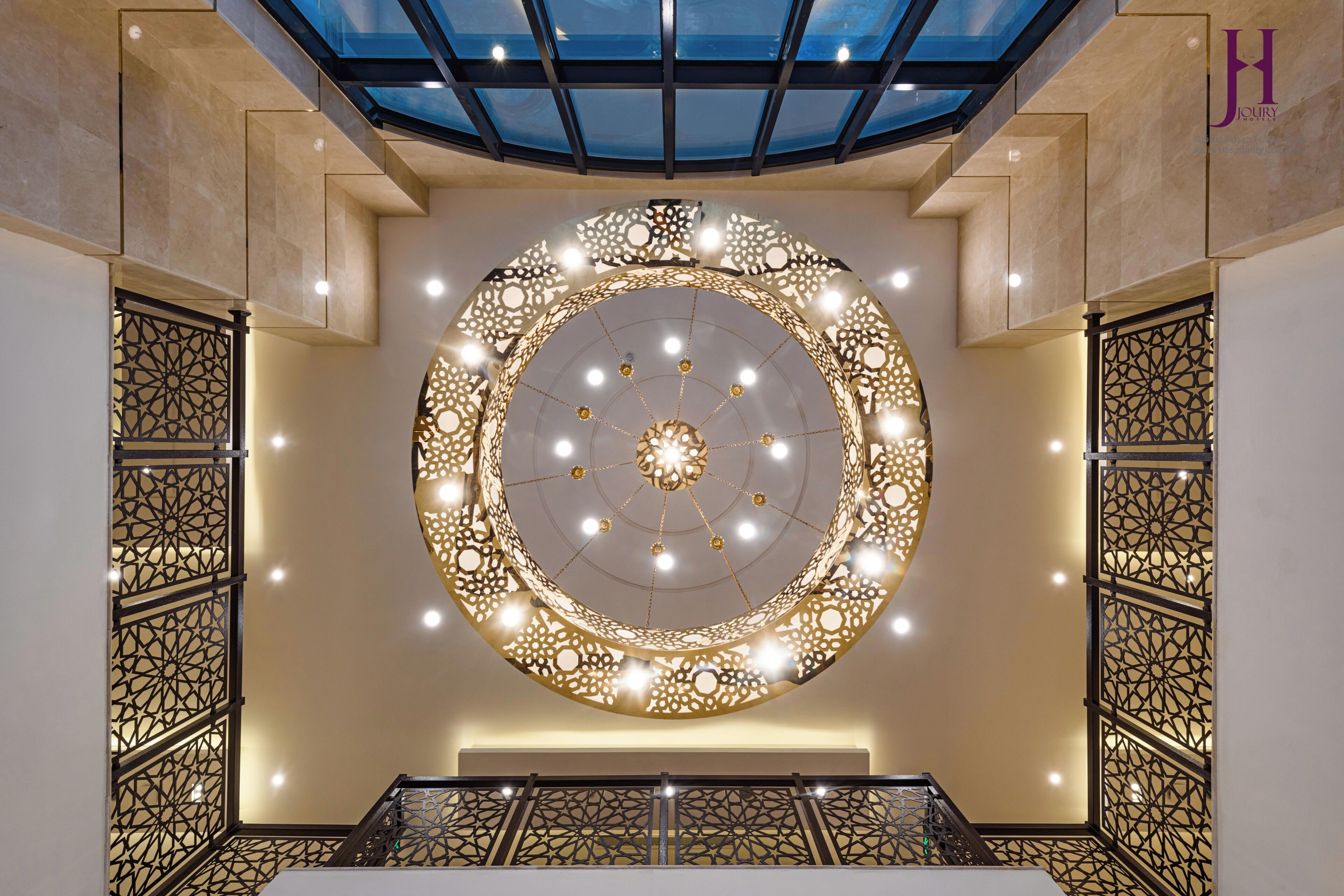 Un techo decorativo circular con patrones intrincados e iluminación, un tragaluz de vidrio arriba y un diseño geométrico en la pared.