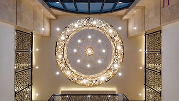 Un techo decorativo circular con patrones intrincados e iluminación, un tragaluz de vidrio arriba y un diseño geométrico en la pared.