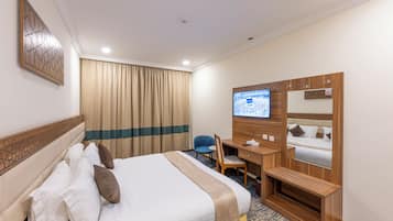 Habitación de hotel con cama, escritorio, silla y televisión en la pared.