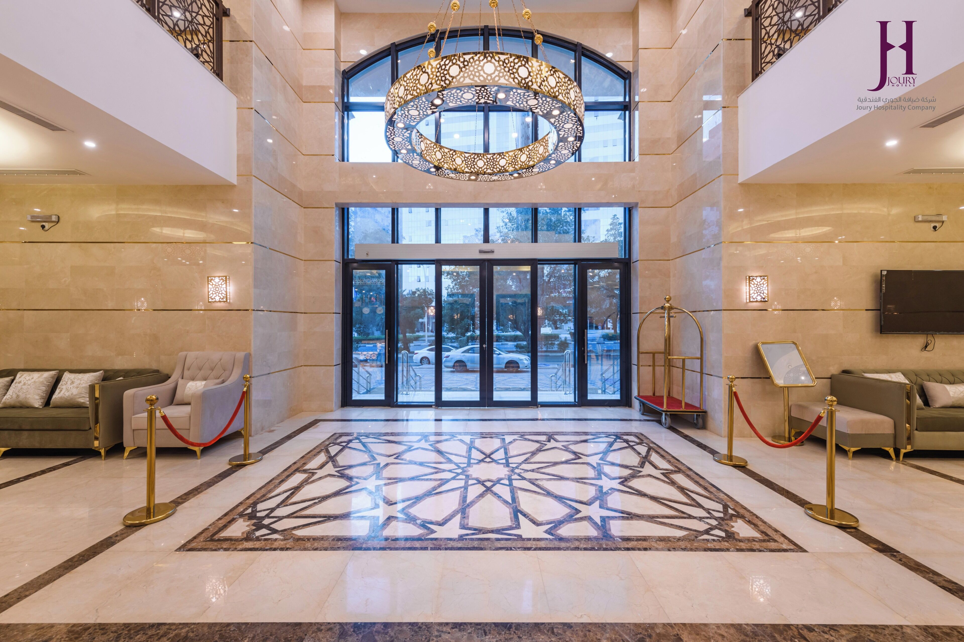 A lobby with a large chandelier, a patterned floor, and a view through the glass doors.
