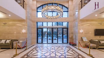 A lobby with a large chandelier, a patterned floor, and a view through the glass doors.