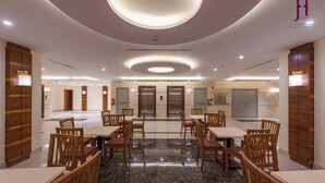 A hotel lobby with a marble floor, wooden chairs and tables, elevators, and a modern ceiling design. - Joury Al Hada Hotel (Makkah)